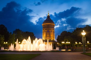 Abbidung des Mannheimer Wasserturms bei Nacht mit Wasserfontainen im Vordergrund